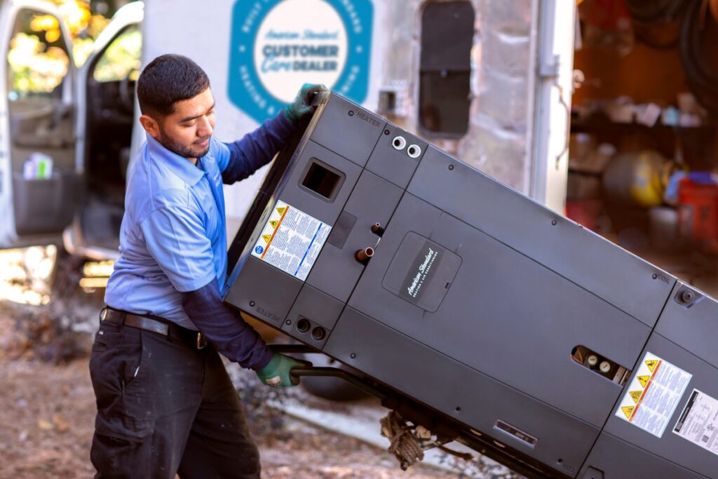 HVAC technician carrying an outdoor condenser unit