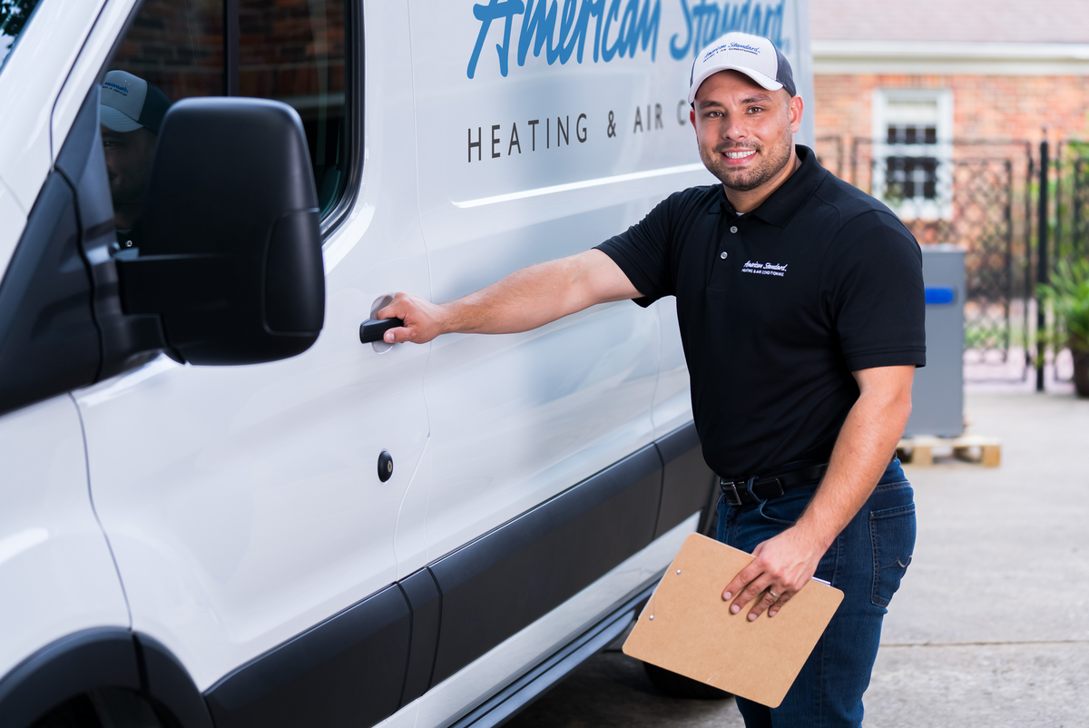 HVAC service technician holding a clipboard beside a service van