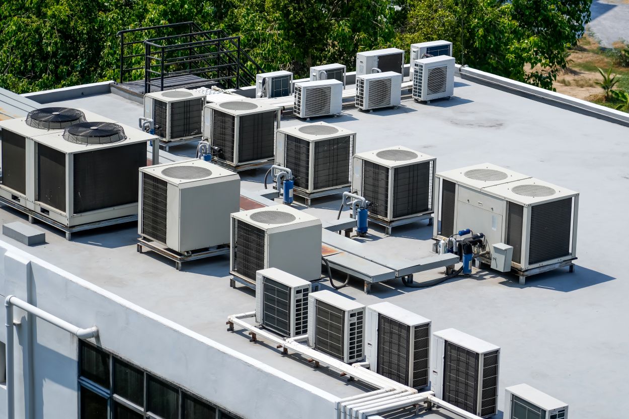 The external units of the commercial air conditioning and ventilation systems are installed on the roof of an industrial building.